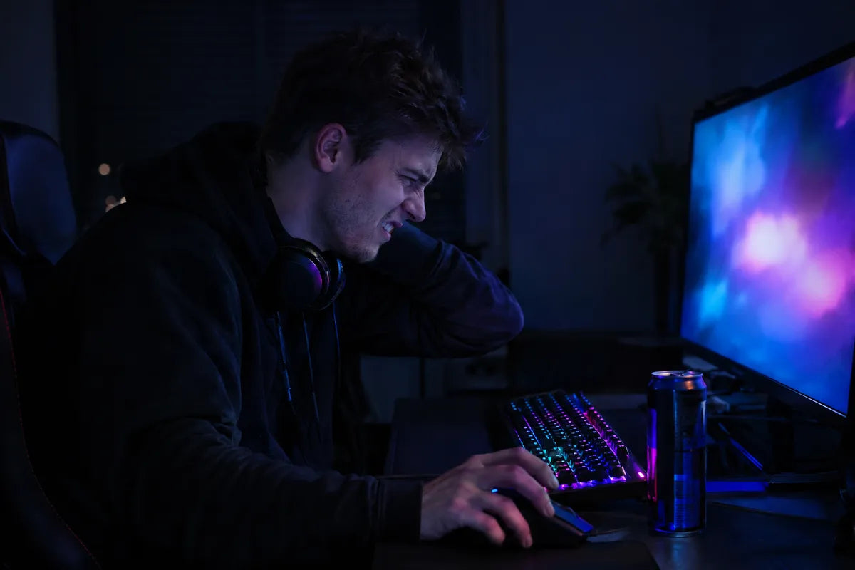 Gamer penché vers son écran, la main sur la nuque